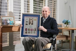 An elderly gentleman poses with his War medals