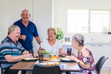 A group of seniors sitting around the coffee table laughing