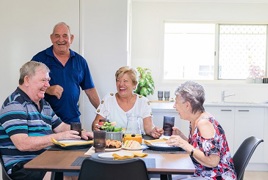 A group of seniors sitting around the coffee table laughing