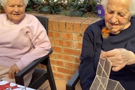Two elderly ladies release a butterfly from its cage
